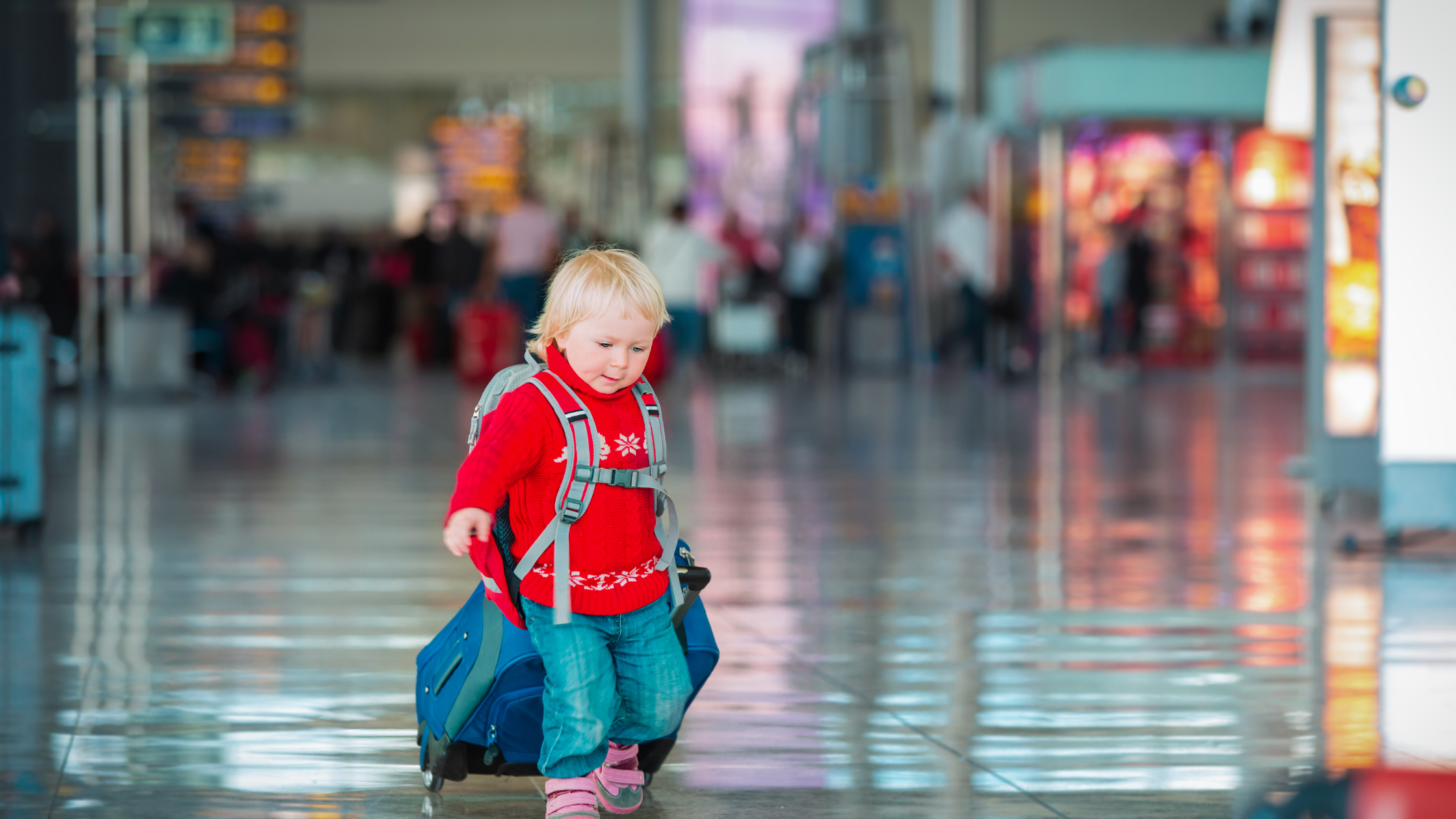small child dragging suitcase through the airport
